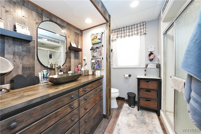 full bath with toilet, wood finished floors, vanity, and a stall shower
