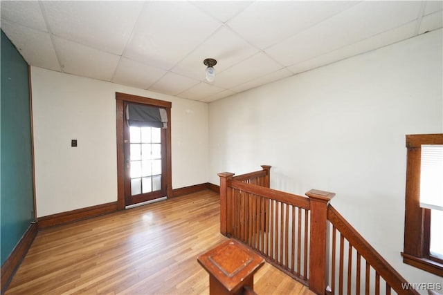 interior space featuring a paneled ceiling, wood finished floors, and baseboards