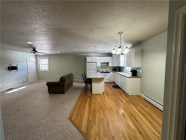 kitchen with a baseboard heating unit, a textured ceiling, open floor plan, and white appliances
