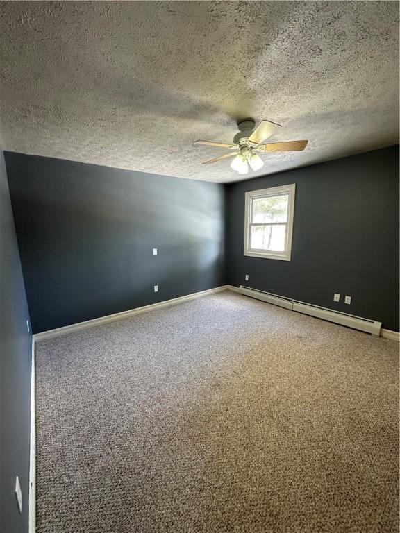 spare room with a ceiling fan, a baseboard heating unit, and carpet floors