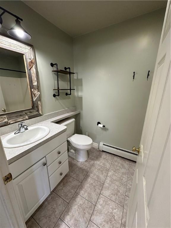 bathroom with tile patterned floors, vanity, toilet, and baseboard heating