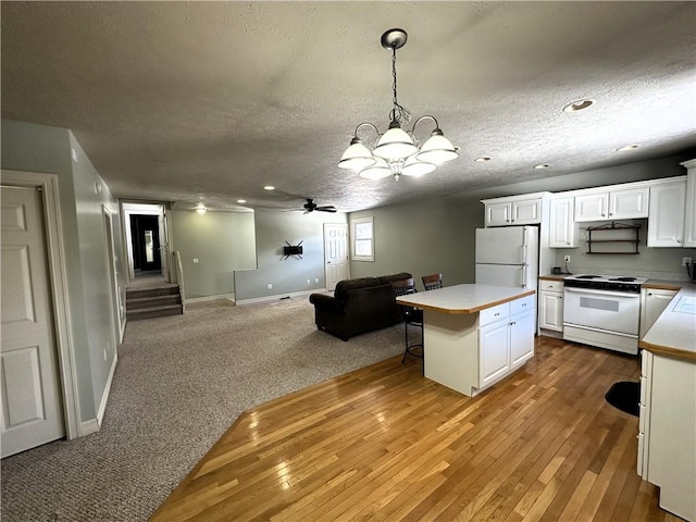 kitchen featuring light wood finished floors, white cabinets, open floor plan, and white appliances