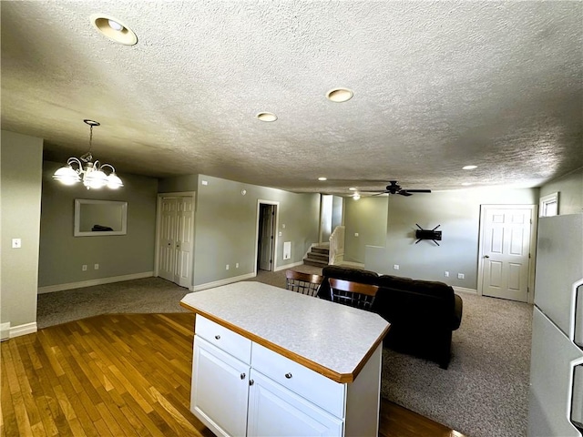 kitchen with white cabinetry, baseboards, a textured ceiling, open floor plan, and dark wood finished floors
