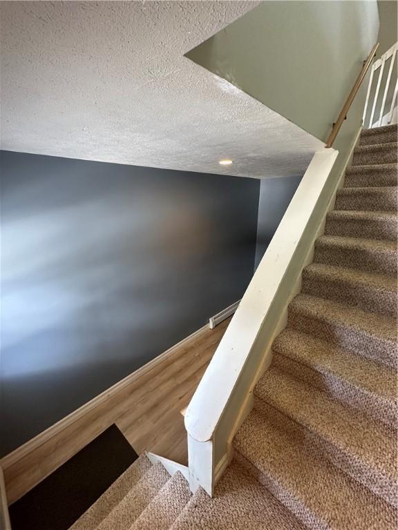 staircase featuring a textured ceiling and wood finished floors