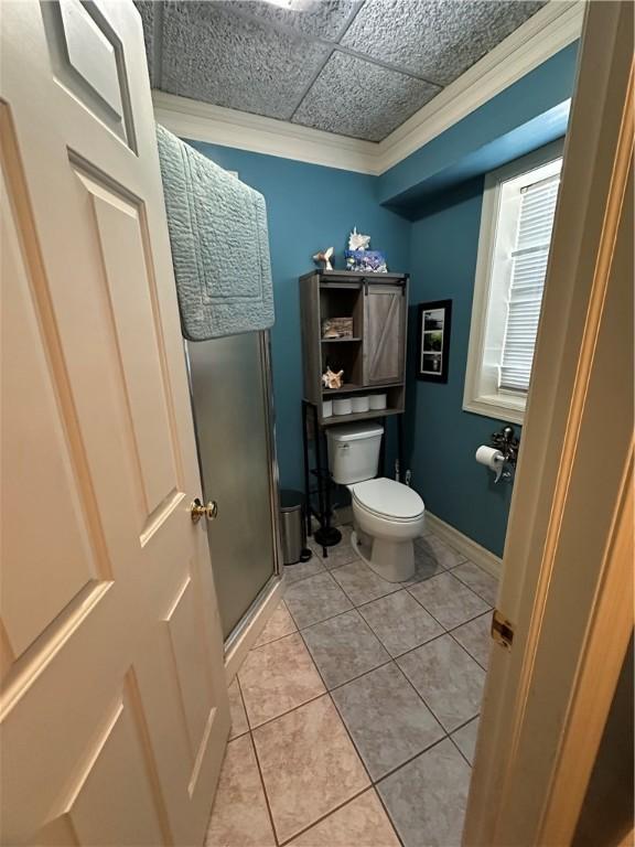 bathroom featuring tile patterned floors, a shower stall, ornamental molding, toilet, and baseboards