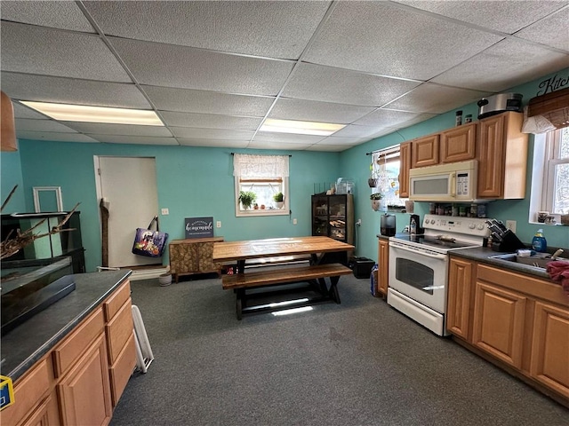 kitchen with dark countertops, white appliances, a paneled ceiling, and a sink