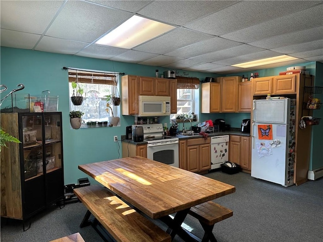 kitchen featuring white appliances, a drop ceiling, dark countertops, a sink, and dark carpet