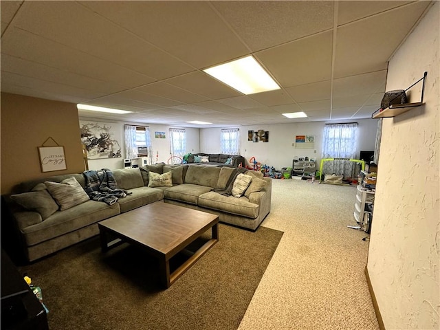 carpeted living area with a paneled ceiling