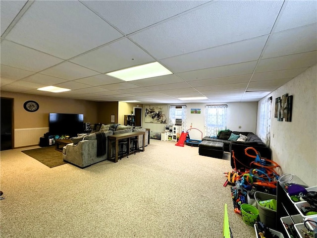 living area with carpet and a paneled ceiling