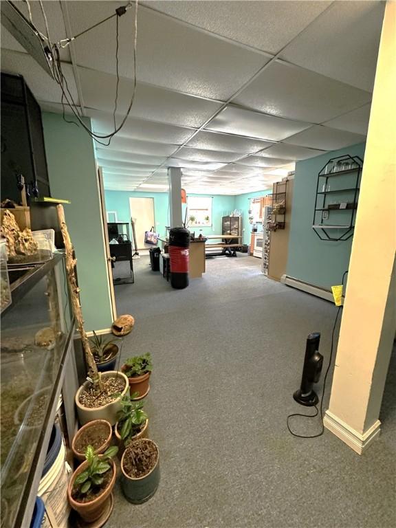below grade area with baseboards, a paneled ceiling, and a baseboard radiator