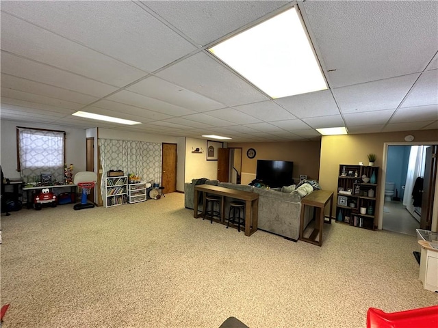 living area with a paneled ceiling and carpet flooring