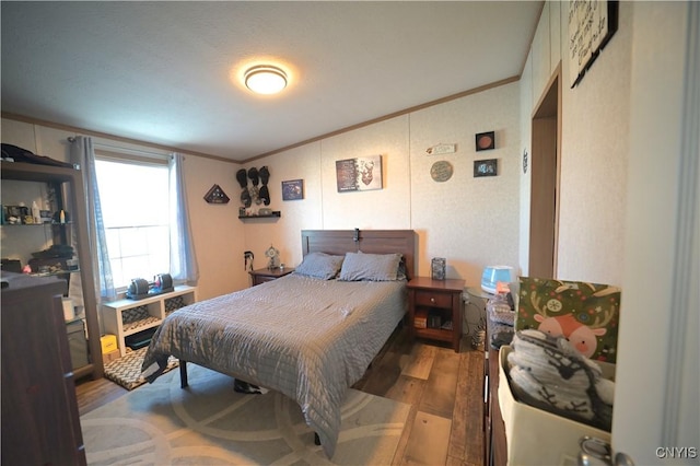 bedroom with lofted ceiling, wood finished floors, and ornamental molding