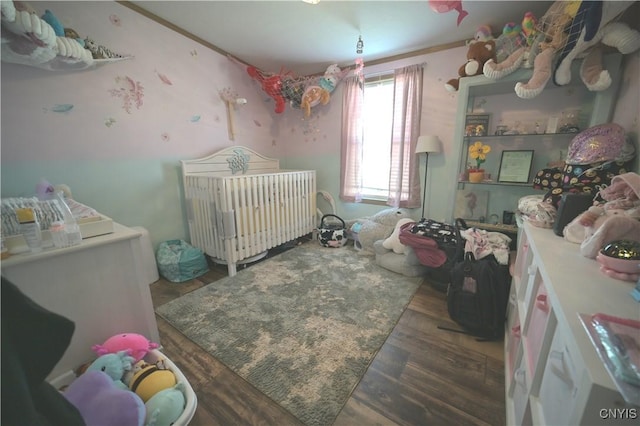 bedroom with radiator heating unit, wood finished floors, and a nursery area
