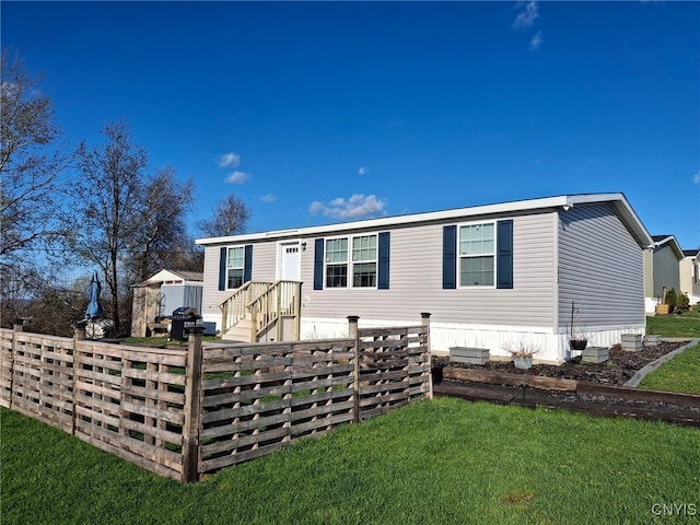 manufactured / mobile home featuring fence and a front lawn