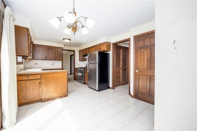 kitchen featuring a sink, stainless steel appliances, light countertops, under cabinet range hood, and a notable chandelier