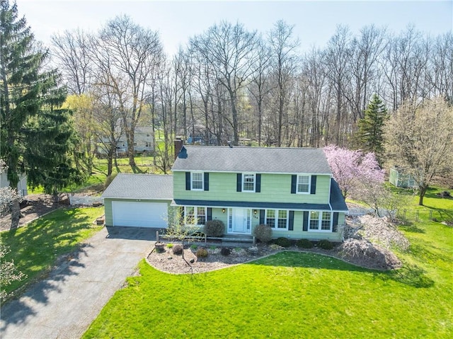 view of front of property featuring a front yard, a chimney, aphalt driveway, and a garage