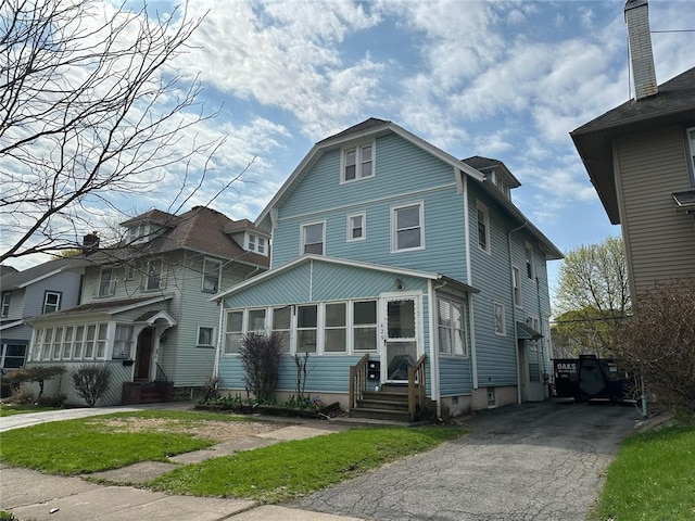 traditional style home with entry steps, aphalt driveway, and a sunroom