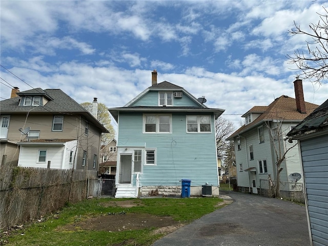 rear view of property with cooling unit, a chimney, aphalt driveway, and fence