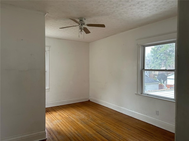 spare room featuring a textured ceiling, wood finished floors, and a healthy amount of sunlight