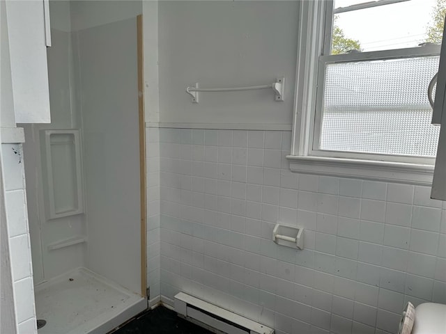bathroom featuring baseboard heating, a shower stall, and tile walls