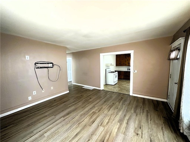 spare room with dark wood-style floors, visible vents, and baseboards