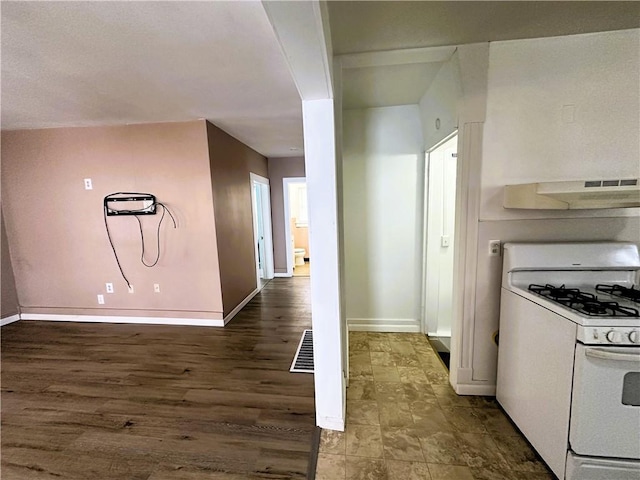 kitchen featuring baseboards, white range with gas cooktop, and under cabinet range hood