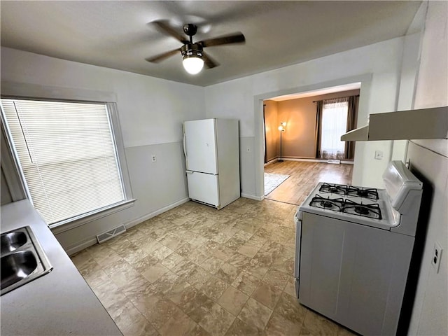 kitchen with white appliances, a sink, baseboards, visible vents, and a ceiling fan