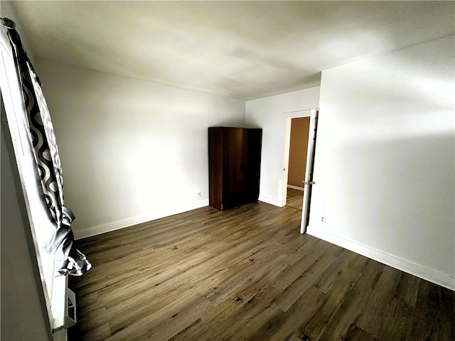 empty room featuring dark wood-style floors and baseboards