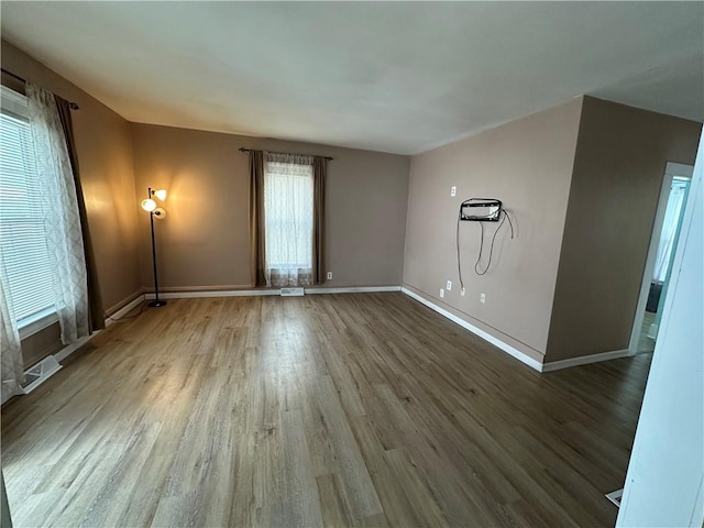 unfurnished room with visible vents, wood finished floors, and baseboards