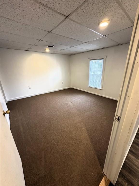 basement with dark carpet, a drop ceiling, visible vents, and baseboards