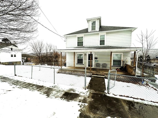 american foursquare style home featuring covered porch, a shingled roof, and fence private yard