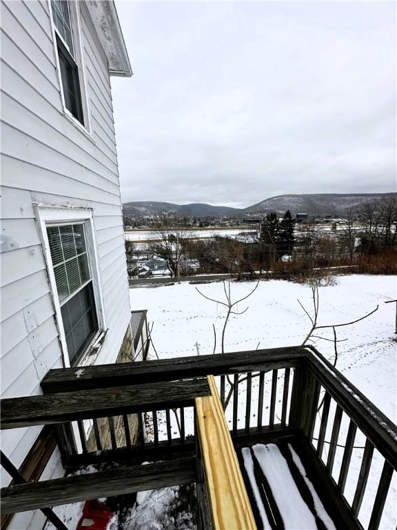 snow covered deck with a mountain view