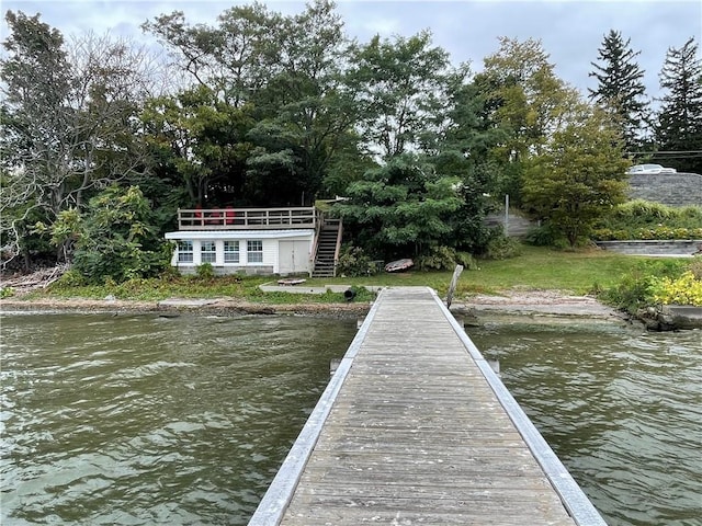 view of dock featuring a yard, a water view, and stairs