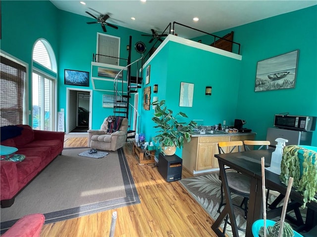 living room with recessed lighting, stairway, ceiling fan, a towering ceiling, and wood finished floors