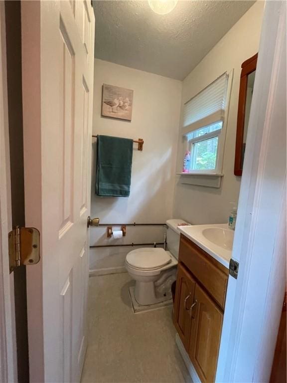 bathroom with toilet, a textured ceiling, vanity, and baseboards