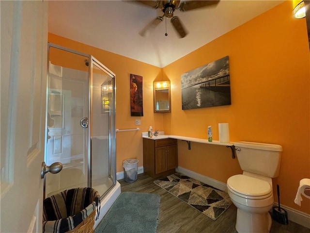 full bathroom with a shower stall, ceiling fan, toilet, wood finished floors, and vanity