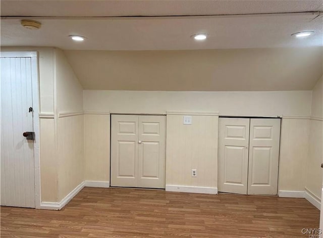 additional living space with recessed lighting, baseboards, lofted ceiling, and light wood-type flooring