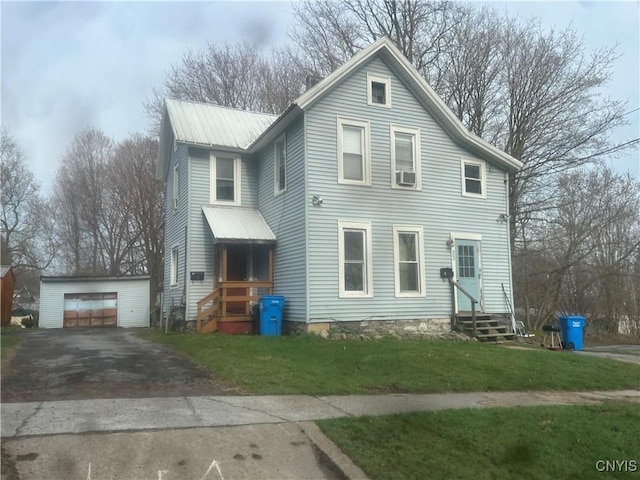 view of front of property featuring a front yard, an outbuilding, metal roof, a detached garage, and entry steps
