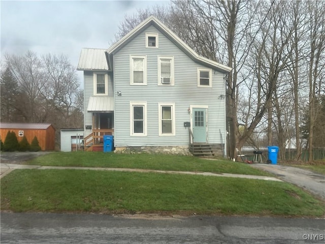view of front of house featuring driveway, entry steps, a front yard, and metal roof