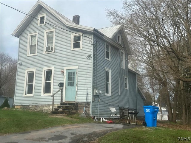 view of front of house with a chimney, entry steps, cooling unit, and a front yard