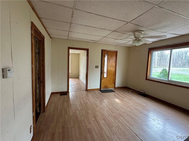 unfurnished room featuring a drop ceiling, a ceiling fan, baseboards, and light wood-style floors