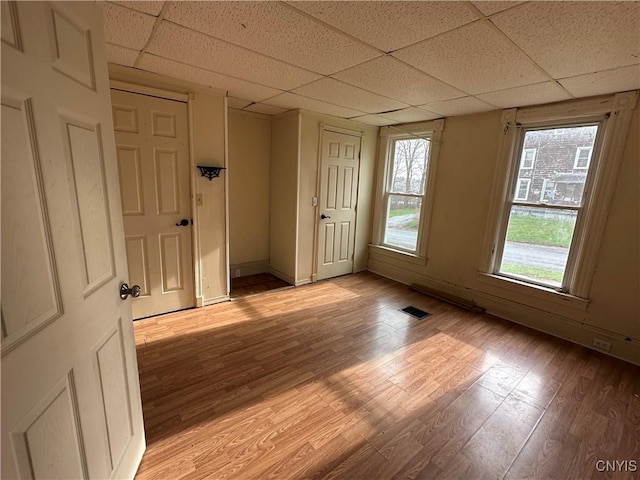 unfurnished room featuring visible vents, light wood-style flooring, and a drop ceiling