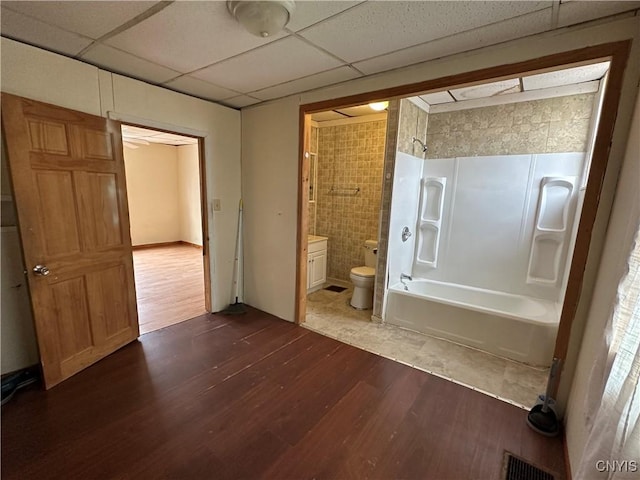 full bathroom featuring tile walls, toilet, visible vents, tub / shower combination, and wood finished floors