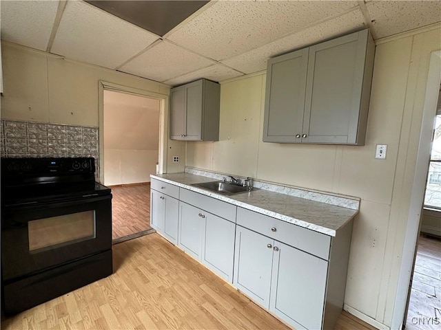 kitchen with gray cabinets, a sink, light wood-type flooring, black electric range oven, and a paneled ceiling
