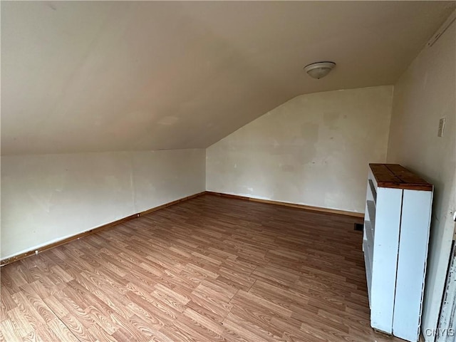 bonus room featuring vaulted ceiling, wood finished floors, and baseboards