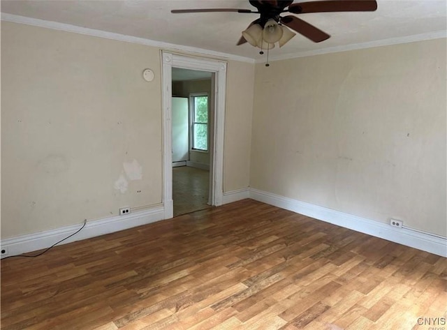 spare room with wood finished floors, a ceiling fan, and baseboards