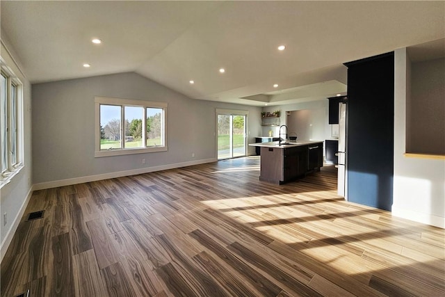 unfurnished living room featuring visible vents, a sink, baseboards, and dark wood finished floors