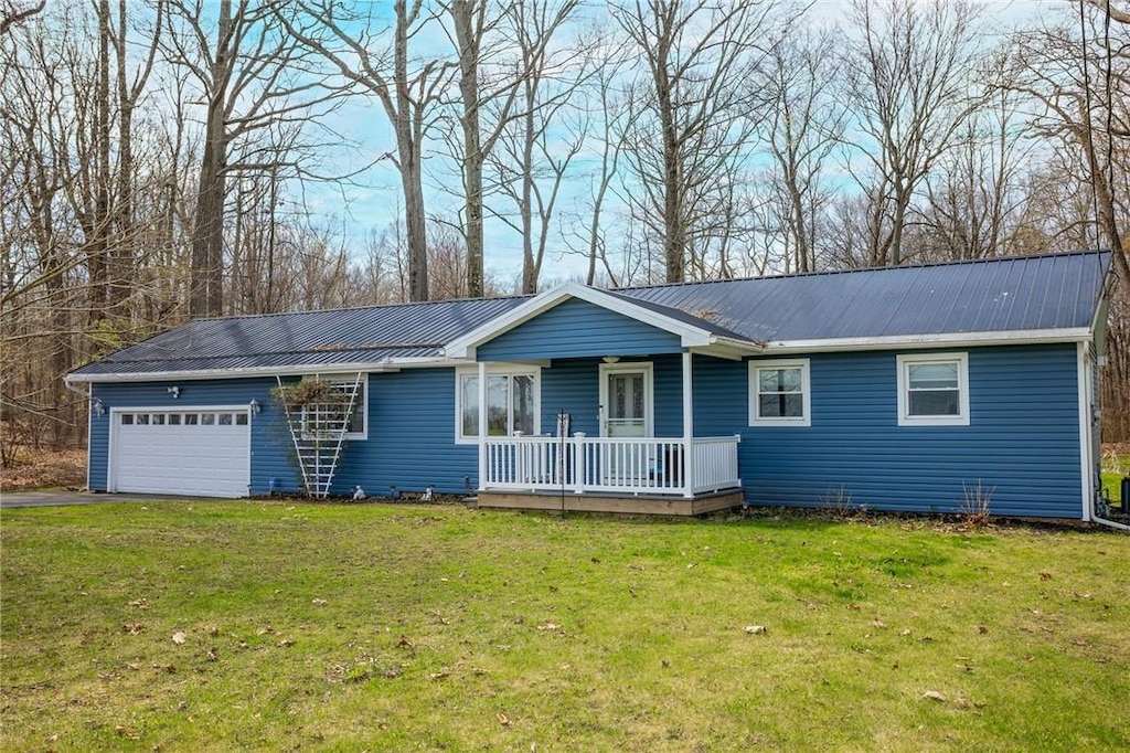 ranch-style house featuring a porch, a front yard, a garage, metal roof, and driveway