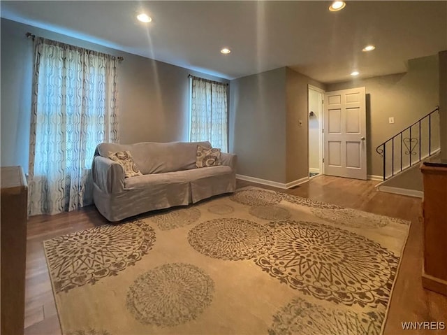 living room featuring stairway, a healthy amount of sunlight, baseboards, recessed lighting, and wood finished floors