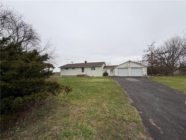 view of front of home featuring an outbuilding, a front yard, a garage, and aphalt driveway